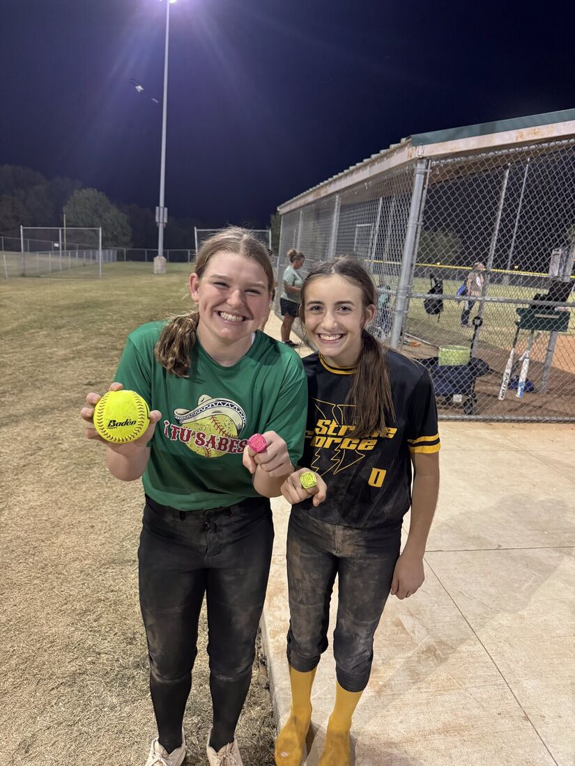 Adeline Camden and a teammate with game balls after a win under the lights