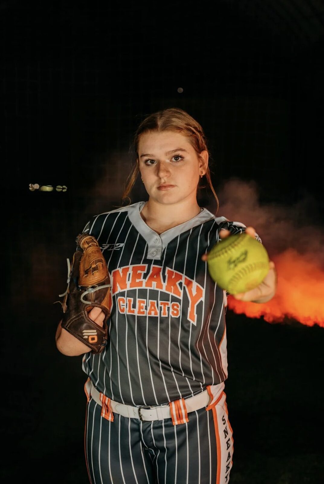 Adeline Camden in Sneaky Cleats uniform holding glove and ball with stadium flare